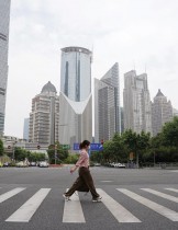 فتاة ترتدي قناع الوجه وهي تعبر طريقًا أمام أبراج المكاتب في منطقة لوجياتسوي المالية، بعد رفع الإغلاق الخاص بفيروس كورونا في شنغهاي ، الصين. رويترز