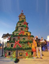 جودي رومانو وجريج رومانو من أريزونا، يقفان لالتقاط صورة سيلفي أمام شجرة عيد الميلاد مصنوعة من مصائد جراد البحر في فلوريدا، الولايات المتحدة.  رويترز