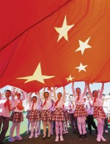 تلاميذ المدارس يحملون علمًا صينيًا عملاقًا قبل الاحتفال باليوم الوطني للبلاد في الأول من أكتوبر. ا ف ب 