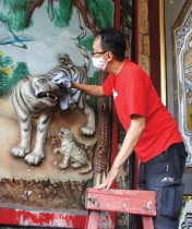 رجل ينظف زخرفة نمر تزين جدارًا في معبد في سيمارانج بجاوا الوسطى، قبل حلول السنة القمرية الجديدة، عام النمر - ا ف ب