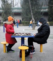 طفل ورجل مسن يلعبان الشطرنج الصيني بحديقة في بكين. ا ف ب