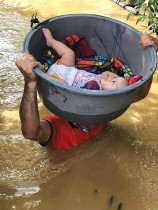 فرد من حرس السواحل يستخدم حوضًا لإجلاء طفل من منزل غمرته الفيضانات في مقاطعة كاجايان، شمال مانيلا. ا ف ب