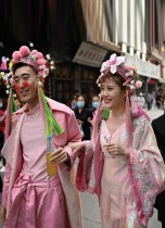 زوجان يرتديان ملابس الأوبرا الصينية يمشيان على طول شارع تجاري في بكين. (ا ف ب) 