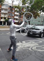 فنان من فناني الشوارع يرتدي قناع الوجه ويؤدي عرضا بهلوانيا عند إشارة ضوئية في مكسيكو سيتي.    (ا ف ب)