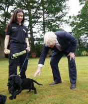 رئيس الوزراء البريطاني مع إحدى موظفات تربية الكلاب البوليسية خلال زيارة لمقر شرطة ساري بالتزامن مع نشر خطة الحكومة للقضاء على الجريمة في جيلدفورد.   رويترز