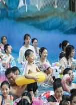 أشخاص يسترخون في قناة مائية للهروب من الطقس الحار في حديقة مائية في هوايان بمقاطعة جيانغسو شرقي الصين. ا ف ب