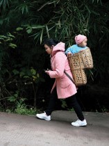 امرأة تحمل طفلاً في سلة على طول شارع بالقرب من جزيرة تشونغبا الصغيرة بالقرب من مدينة تشونغتشينغ الصينية. ا ف ب