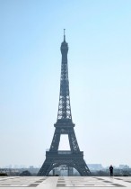 شرطي يسير بالقرب من برج إيفل التاريخي في باريس والمهجور حاليا بفعل المخاوف من انتشار فيروس كورونا.(أ ف ب)