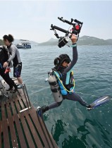 غواصًة شابة تحمل كاميرا تحت الماء وتقفز في البحر قبالة ساحل ساي كونغ في هونغ كونغ لإجراء أبحاث عن الأسماك لمنظمة بلوم البيئية غير الحكومية NGO.   ا ف ب