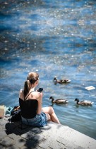 امرأة تستمتع بالشمس في باريس على ضفاف نهر السين بينما يسبح البط أمامها، حيث تخفف فرنسا من إجراءات الإغلاق. ا ف ب