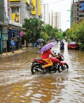 رجل يسير بدراجته النارية حاملا مظلة في طريق غمرته المياه تحت المطر في كولكاتا ،بالهند. ا ف ب