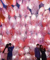 أشخاص يلتقطون صورًا «سيلفي» بجوار عرض مظلات مزينة بأضواء لمهرجان المصابيح القادم في شارع تجاري في هانغتشو بمقاطعة تشجيانغ بشرق الصين. ا ف ب