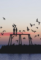 طيور تحلق فوق التمثال الذي يحمل عنوان زوجين للفنان البريطاني شون هنري عند الفجر في نيوبججين، نورثمبرلاند ، بريطانيا. رويترز