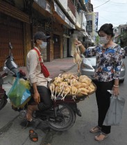 امرأة تشتري دجاجة من بائع على طول الشارع حيث ظلت الأسواق مغلقة وسط قيود الإغلاق بسبب بفيروس كورونا في بنوم بنه (ا ف ب) 