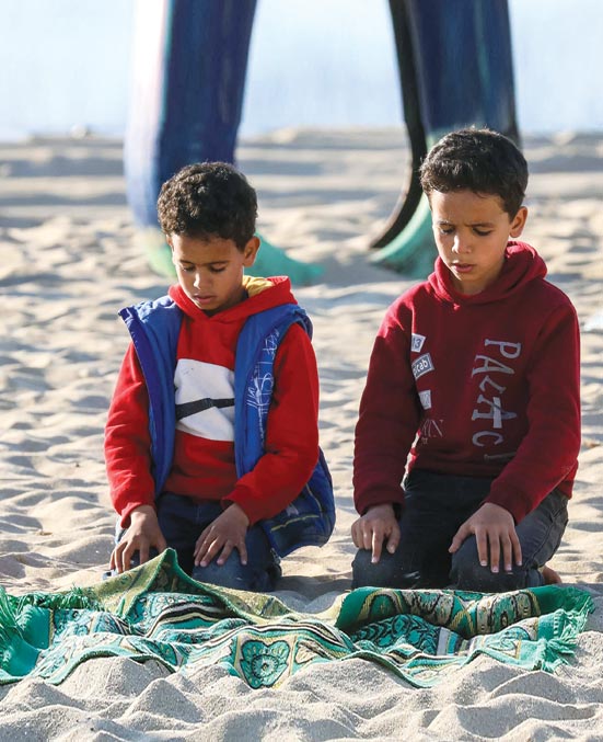 طفلان يصليان على طول شاطئ البحر المتوسط في مدينة بنغازي شمال شرق ليبيا خلال شهر رمضان المبارك. (ا ف ب)