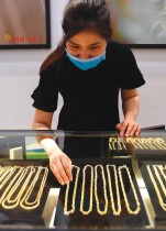 موظفة ترتدي قناع وجه وتقوم بترتيب المجوهرات في متجر للذهب في العاصمة الفيتنامية هانوي. ا ف ب