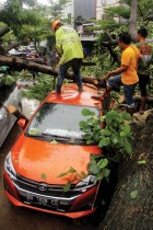 أشخاص يزيلون شجرة سقطت على السيارات بعد هطول أمطار غزيرة في ماكاسار ،إندونيسيا - ا ف ب