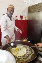 عامل ليبي يضيف البيض إلى الخبز المقلي ويسمى (السفينز) الذي يقدم للزبائن خلال شهر رمضان في طرابلس. (ا ف ب)