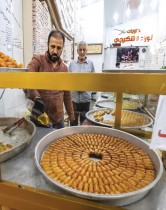 بائع يصب الزيت على صينية من المعجنات الحلوة خلال شهر رمضان المبارك في محل حلويات في منطقة الصدرية وسط بغداد. (ا ف ب)